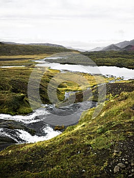 Cold water in Iceland. Stream in rocky mountains and lake side.