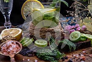 Cold water with lemon, kaffir lime, cucumber and mint leave on wooden background
