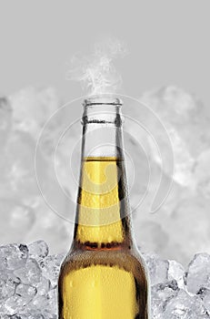 Cold wet open beer bottle with smoke on ice cubes background