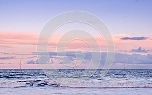 A cold winter afternoon walk at the beach. Win turbines windmills with cloudy sky in the background. Pastel colors horizontal im