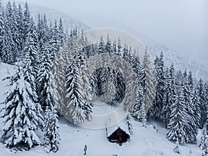 Cold winter morning in mountain foresty with snow covered fir trees. tatras, slovakia. Aerial view. Cabin alone in snow forest.