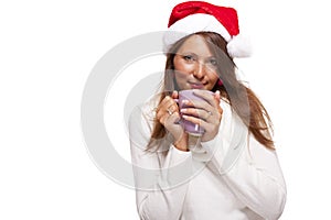 Cold young woman in a Santa hat sipping coffee tea