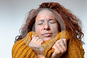 Cold young woman snuggling into a winter top