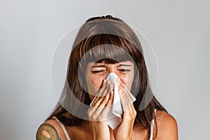 Colds and seasonal viral diseases. A brunette woman sneezes or blows her nose in a handkerchief. Copy space