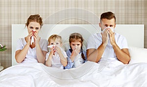 Colds and viral diseases. family with runny nose and fever in bed