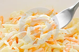 Coleslaw salad with carrot and cabbage on fork.