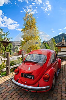 COLFOSCO, ITALY - SEP 26, 2013: Vintage red Volkswagen VW Beetle car parked in front of a house in alpine village Colfosco,