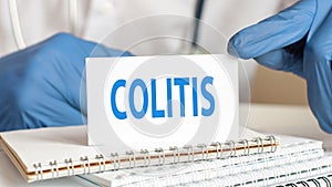 Colitis card in hands of Medical Doctor, hands in blue glove with white small card