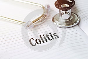 COLITIS text on white paper on the white background. stethoscope ,glasses and keyboard