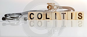 COLITIS the word on wooden cubes, cubes stand on a reflective white surface, on cubes - a stethoscope