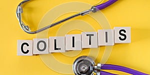 COLITIS the word on wooden cubes on yellow background, near cubes - a stethoscope. Medicine concept