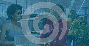 Collaborating colleagues viewing graphs on laptops at open-plan office, with mugs, pens and plants