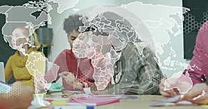 Collaborating students crafting project in classroom with colored paper and notebooks under AR map