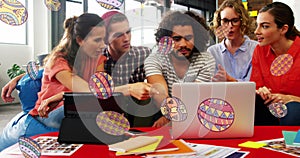 Collaborating team members pointing at laptop in modern lounge, with tablet and egg graphics photo