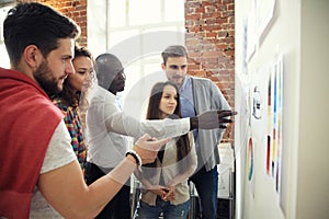 Collaboration is a key to best results. Group of young modern people in smart casual wear planning business strategy photo