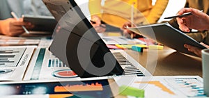 Collaborative Business Meeting with Diverse Professionals Analyzing Data on Digital Devices and Paper Reports in Bright