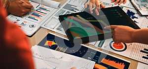 Collaborative Business Meeting Emphasizing Data Analysis with Digital and Printed Graphs on a Table Surrounded by