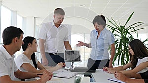 Collaborators standing near desk in white modern office discuss possibilities