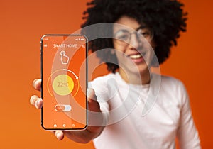 Collage with black man showing remote smart home control system on mobile phone screen, orange background