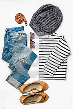 Collage of female clothing set. Ripped jeans, striped blouse, brown high heels shoes and accessories over white wood background.