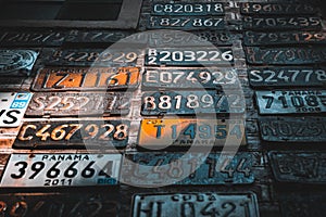 Collage of old, rusty and grungy car license plates over a brick wall illuminated by sun rays