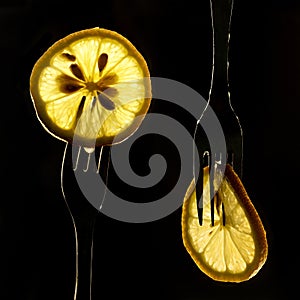 Collage of three slices of lemons on the fork on dark black background. silhouette of a fork in the back light. Drops of juice