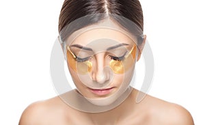 Collagen gold patches under the eyes against wrinkles and dry skin on the face of a beautiful woman. Female aesthetic cosmetology