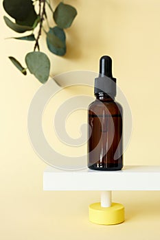 Collagen peptide serum facial moisturizer bottle standing on abstract pedestal on pastel yellow background with copy space photo