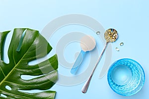 Collagen powder and capsules vitamin d-3 on a blue background with a beautiful green leaf.