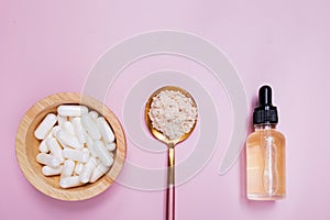 Collagen products serum, powder and pills on pink background