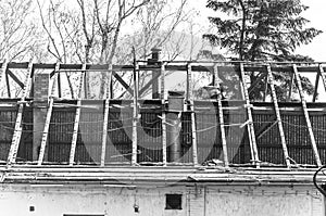 Collapsed roof of old abandoned house with wooden beams, damaged and destroyed in war zone or dramatic nature disaster, black and