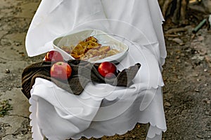 Collapsed soft baked apples in a white ceramic square shape on a special package. A white tablecloth is laid carelessly on the tab