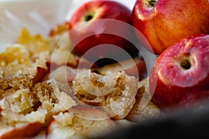 Collapsed soft baked apples in a white ceramic square shape on a special package. A white tablecloth is laid carelessly on the tab