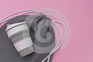 Collapsible silicone eco mug and mesh bag on pink background