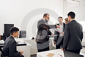 Colleages stand and look at their chief with documents in his hands