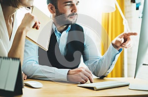 Colleague designer consultant discuss startup project. Bearded young businessman working at office looking in monitor computer