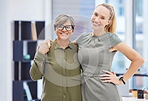 Colleagues are best friends in disguise. two businesswomen standing together in the office with their arms around each