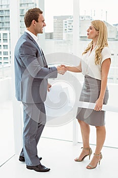 Colleagues with blueprints shaking hands
