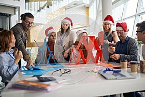 Colleagues in bright office having fun for  christmas, building paper towers at work, playing