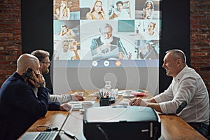 Colleagues, business people meeting with employees via online video call in conference room for project discussion