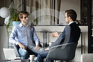 Colleagues businessmen discussing project strategy, sitting in modern office