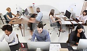 Colleagues at computers in an open plan office, front view