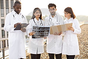 Colleagues coworking with indian man showing results of patient's tests.