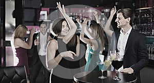 Colleagues dancing on corporate party with cocktails in hands