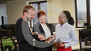 Colleagues are discussing documents. African young woman, caucasian man and red-haired caucasian woman communicate in