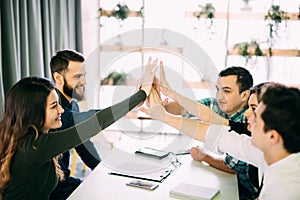 Colleagues giving high-five in meeting room at creative office