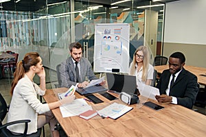 Colleagues having working discussion during meeting in office boardroom. Group of business people working together