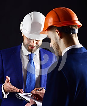 Colleagues in helmets discuss building plans.