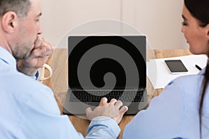 Colleagues At Laptop With Empty Screen Working In Office, Back-View