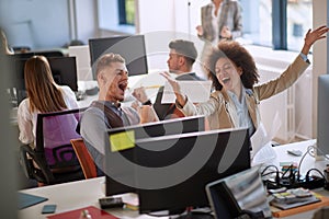 Colleagues, male and female, sharing a good news at work. woman throwing papers from happiness, man raised his fists. good news at